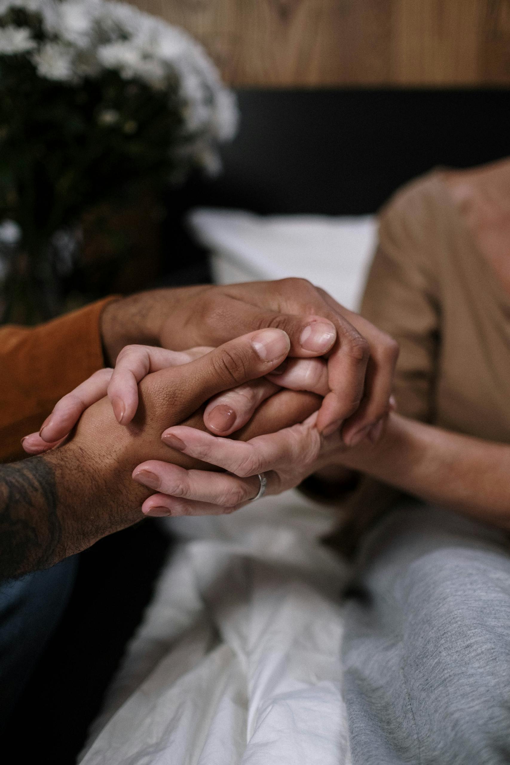 A close-up of diverse hands clasped together symbolizing comfort and support.