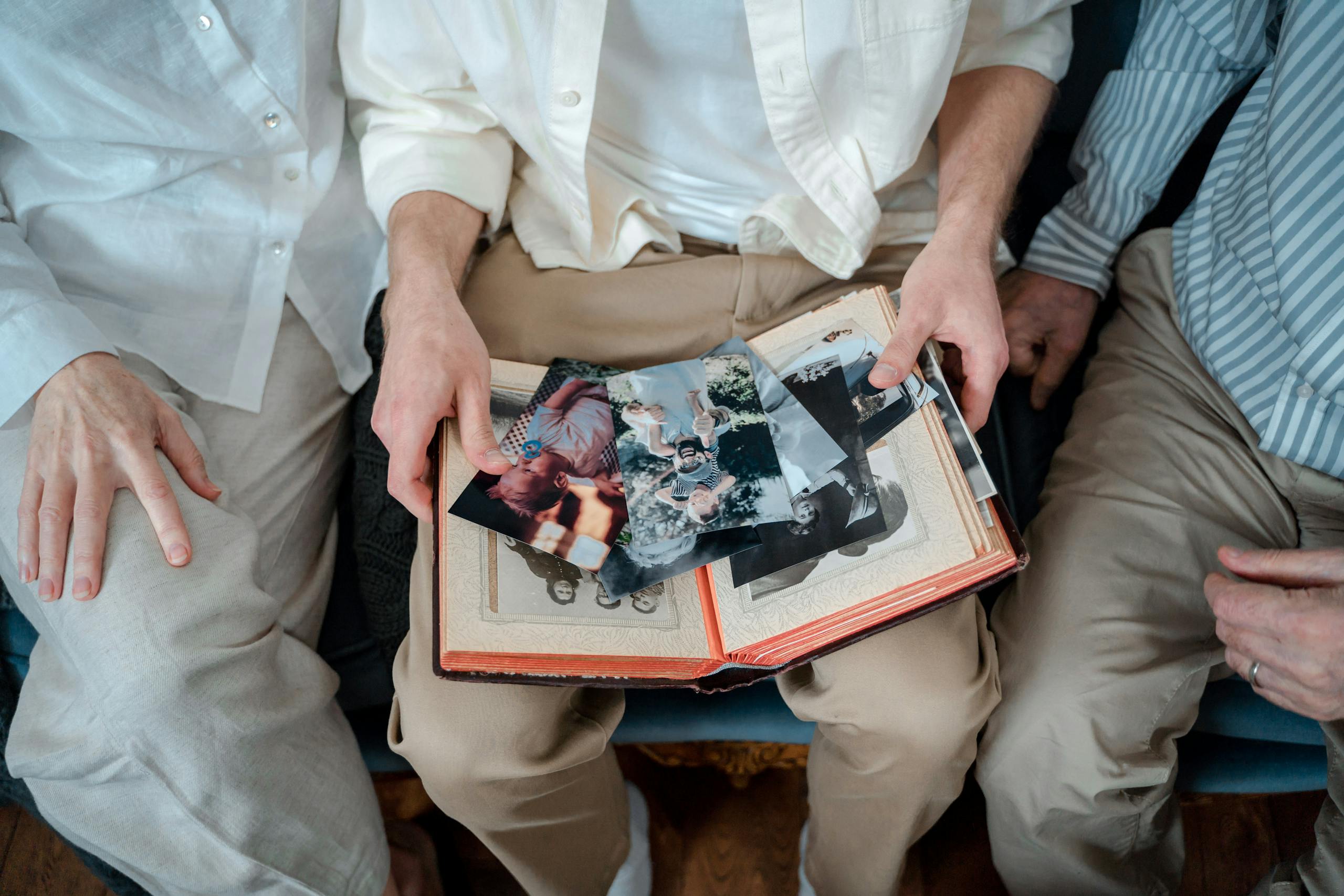 A family of three enjoying old photos together, sharing cherished memories.