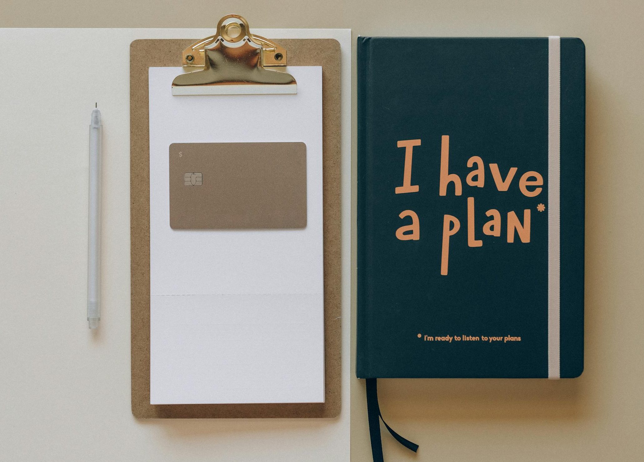 A minimalist office setup featuring a planner, clipboard, card, and pen, perfect for planning and organization.